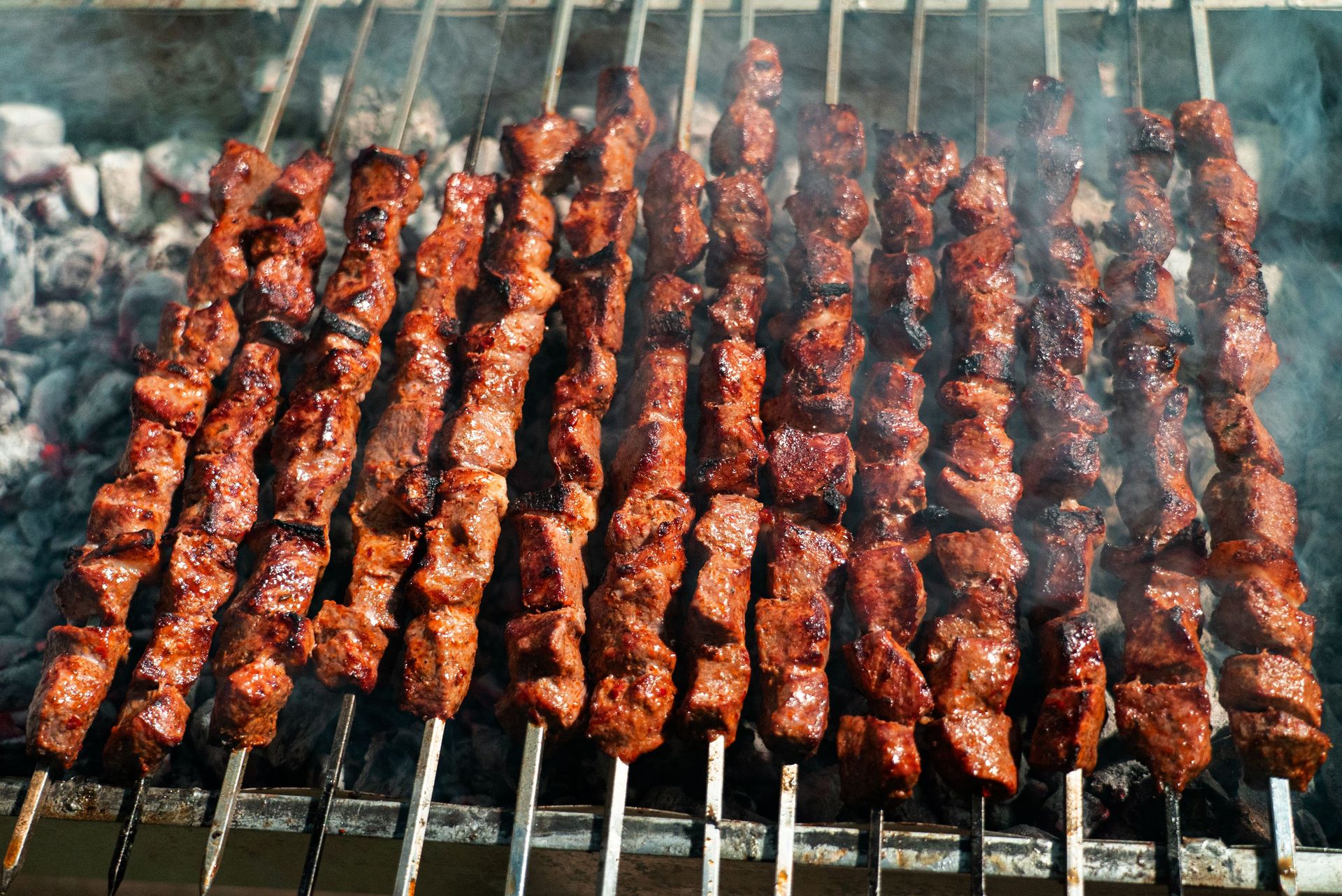 Juicy beef skewers sizzling on an open charcoal grill, perfect for summer BBQ.